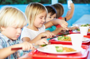 Elementary Pupils Enjoying Healthy Lunch In Cafeteria